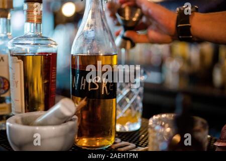 Nahaufnahme der Whiskey Flasche mit bartender Drink in Gießen zurück Stockfoto