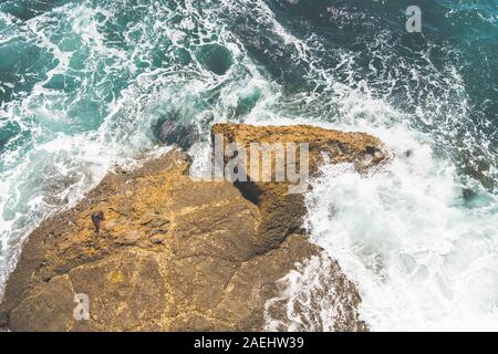 Wellen gegen einen Felsen Stockfoto