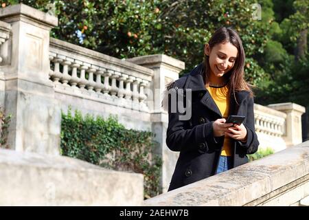 Junge Frau in Gelb gekleidet und trägt einen blauen Regenmantel sprechen mit Ihrem Handy und gehen die Treppe zur gleichen Zeit. Kommunikation anhand von quantitativen Simulatio Stockfoto