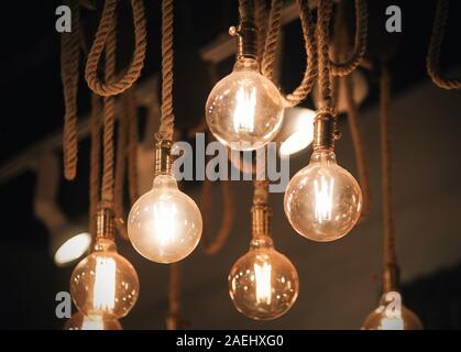 Schöne Einrichtung für den Innenraum - Eine runde Glas leuchtende gemütliches Licht der Lampen hängen an den dicken hempen Seile. Stockfoto
