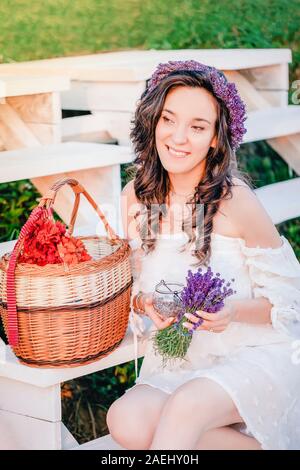 Schöne Mädchen in weißem Kleid mit lila Lavendel Blumenstrauß Stockfoto