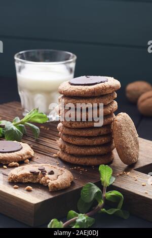 Gesunde vegane Spezialitäten. Peanut Butter und Mandeln Kekse mit Schokolade Tropfen serviert mit der Milch und Minze auf dunklem Hintergrund copyspace Stockfoto