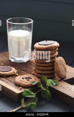 Gesund vegan Glutenfrei zuckerfrei Frühstück. Erdnussbutter, Haferflocken und almond Cookies mit Schokolade Tropfen serviert mit der Milch und Minze auf dunklen Stockfoto