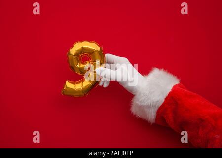 12 Tage von Weihnachten. Santa Hände halten 9. tag Ballon auf rotem Hintergrund Stockfoto