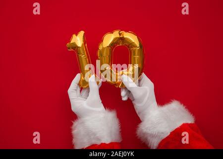 12 Tage von Weihnachten. Santa Hände halten 10. Tag Ballon auf rotem Hintergrund Stockfoto