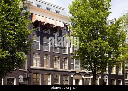 Blick auf die historische, traditionelle und typische Gebäude zeigen Niederländische architektonischen Stil und Bäume in Amsterdam. Es ist ein sonniger Sommertag. Stockfoto