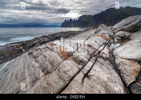 Küste bei Tungeneset, Blick über Zähne spitzen Rock Formation des berühmten Teufel der Bergkette Okshornan, Insel Senja, Troms, Norwegen im Norden. Stockfoto