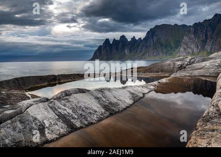 Küste bei Tungeneset, Blick über Zähne spitzen Rock Formation des berühmten Teufel der Bergkette Okshornan, Insel Senja, Troms, Norwegen im Norden. Stockfoto