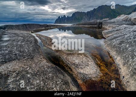 Küste bei Tungeneset, Blick über Zähne spitzen Rock Formation des berühmten Teufel der Bergkette Okshornan, Insel Senja, Troms, Norwegen im Norden. Stockfoto