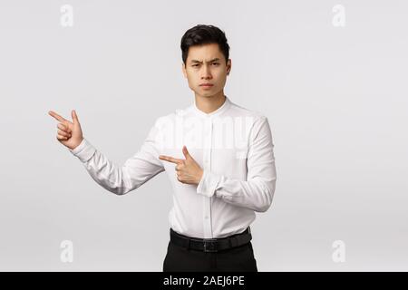 Ernst - auf der Suche strenge und unzufriedenen jungen asiatischen Mann enttäuscht mit Malerei hing schief. Unternehmer suchen Kamera Schmollen und runzelte die Stirn Stockfoto