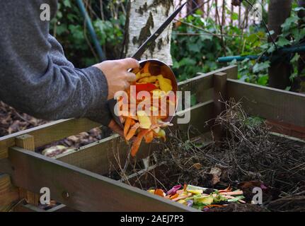 Ökologie Kompost versorgen - Küche das Recycling von Abfällen im Hinterhof Komposter. Umweltfreundlichen Lebensstil. Der Mann wirft übrig gebliebene Gemüse aus. Stockfoto