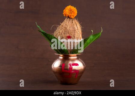 Kupfer kalash mit Kokos und Mango leaf mit Blumendekor auf einer hölzernen Hintergrund. Wesentlichen in der hinduistischen Puja. Stockfoto