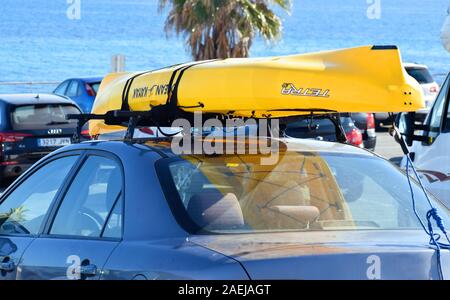 Murcia, Spanien, 20. August 2019: Gelb mit dem Kajak auf dem Dachgepäckträger gegen Palmen gebunden, und die Marine in Barcelona, Spanien. Stockfoto