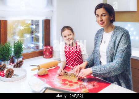 Weihnachtsbäckerei. Mutter und Tochter, Lebkuchen, schneiden Cookies von Lebkuchen Teig. Festliche Essen, Kochen, kulinarisch, Christus Stockfoto