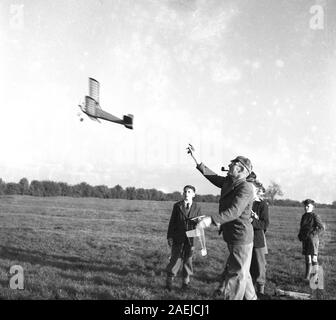 1950, historische, draussen auf einer Wiese, einige Jungen auf der Suche nach einem Erwachsenen Enthusiast ein flugmodell Flugzeug in die Luft, England, Großbritannien startet. Stockfoto