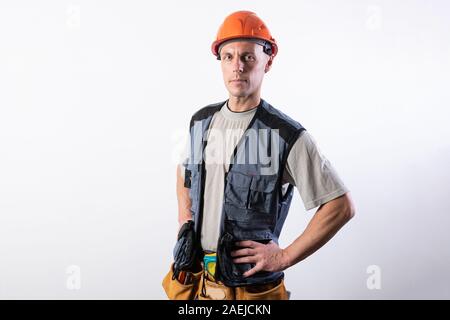 Der Bauherr legte die Hände auf seine Hüften. In Arbeitskleidung und harten Hut. Stockfoto