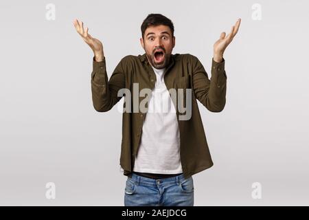 Schockiert und beschämt, bärtigen Mann in Panik, heben Sie die Hände hoch seitlich verdutzt und verwirrt, frustriert und sprachlos, keuchende stare Kamera Stockfoto