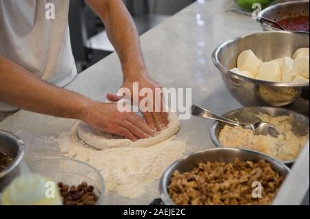 Vorbereitung Pizza dought auf einem Ablageflächen aus Marmor. Tomatensauce, Mozzarella und anderen Zutaten Notunterstände im Vordergrund. Stockfoto