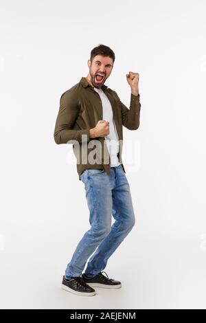 Leistung, Ziel und Konzept gewinnen. In voller Länge vertikaler Fröhliche stattlichen erfolgreicher Geschäftsmann in lässigem Outfit, Tanzen triumphiert und Stockfoto