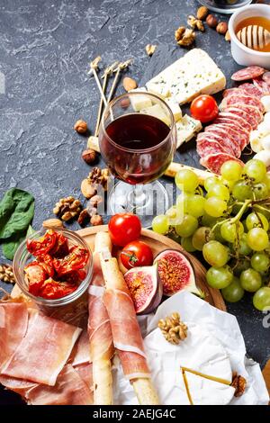 Italienische Antipasti mit Schinken, Schinken, Käse, Oliven und Grissini Grissini auf schwarzem Stein. Stockfoto