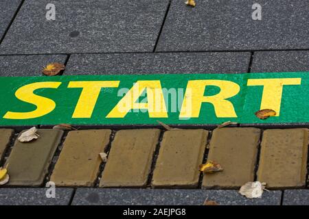 Ort als Start markiert. Ein Platz, zum zu beginnen und neue Erfolge. Symbolisches Zeichen auf dem Bürgersteig. Stockfoto