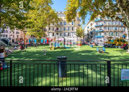 Kinder spielen in einem kleinen eingezäunten Spielplatz Schulhof in das städtische Zentrum von Nizza, Frankreich. Stockfoto