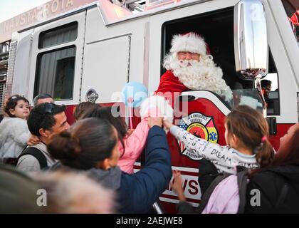 Santa Claus begrüßt die Kinder, wie er durch Feuer Lkw während der jährlichen Weihnachtsbaum kommt-beleuchtung Winter Wonderland Fall an der U.S. Naval Station Rota Dezember 7, 2019 in Rota, Spanien. Stockfoto