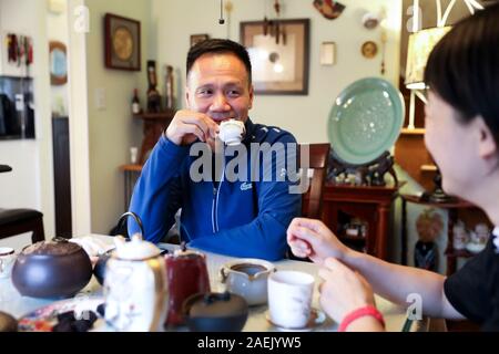 New York, USA. Nov, 2019 20. Chen Sitan (L) spricht mit seiner Frau Lin Xu beim Trinken von chinesischen Tee an ihrem Haus in Syosset, New York, USA, Nov. 20, 2019. Die alte chinesische Kampfkunst Tai Chi hat immer eine Form des Lebens für viele New Yorker geworden, dank der Bemühungen durch ehemalige Welt Kampfkunst Meister Chen Sitan und seine Frau Lin Xu. GEHEN MIT 'Feature: Der ehemalige Weltmeister bringt Tai Chi in das Leben "Credit New Yorker': Wang Ying/Xinhua/Alamy Leben Nachrichten aus Stockfoto