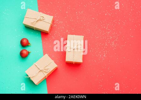 Null Abfall umweltfreundliche Weihnachten. Ansicht von oben Präsentiert in braun Handwerk Papier gewickelt, auf festlichen glitzerndem grünen und roten Hintergrund, Kopieren, selektiven Fokus Stockfoto