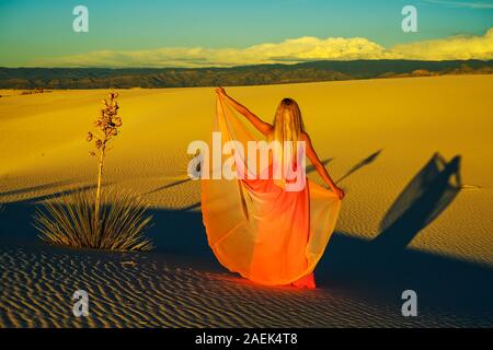 Traum - wie Szene. Elegante Frau, trug einen Fancy Dress und stehen wie ein Märchen unter den Yuccas bei Sonnenuntergang in der Wüste von White Sands National Monu Stockfoto