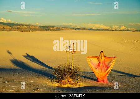 Traum - wie Szene. Elegante Frau, trug einen Fancy Dress und stehen wie ein Märchen unter den Yuccas bei Sonnenuntergang in der Wüste von White Sands National Monu Stockfoto