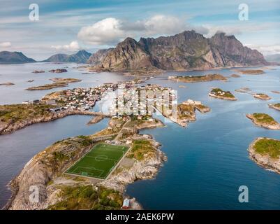 Unglaubliche Luftaufnahme von henningsvær, seine malerische Fußballplatz und die Berge im Hintergrund. Ein kleines Fischerdorf auf mehrere kleine ist Stockfoto