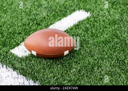 Eine braune Fußball auf einem weißen Raute auf grünem Rasen Feld platziert. Stockfoto