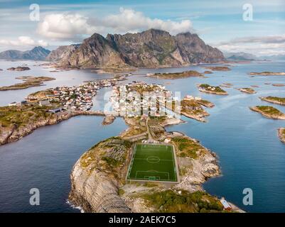 Unglaubliche Luftaufnahme von henningsvær, seine malerische Fußballplatz und die Berge im Hintergrund. Ein kleines Fischerdorf auf mehrere kleine ist Stockfoto