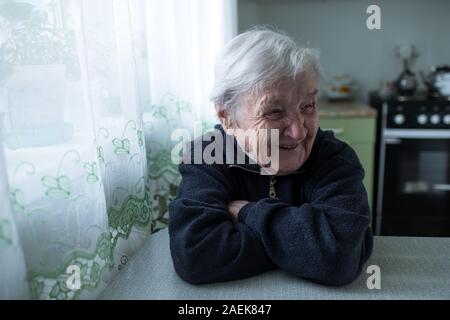 Alte Frau lacht am Tisch sitzen. Ältere Menschen und Rentner. Stockfoto