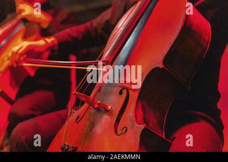 Cello Konzert mit Instrument. Rot leuchtenden Hintergrund bei Rock Konzert Stockfoto