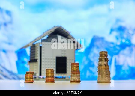 Vier Stapel von Münzen mit Größe immer von rechts nach links jedes Quartal, mit einem Haus im Hintergrund. Konzept für Sav Stockfoto