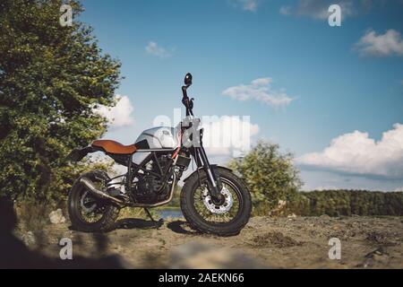 Café Racer scrambler Motorrad, altmodischen Fahrzeug mit modernen Materialien auf Wald Hintergrund Stockfoto