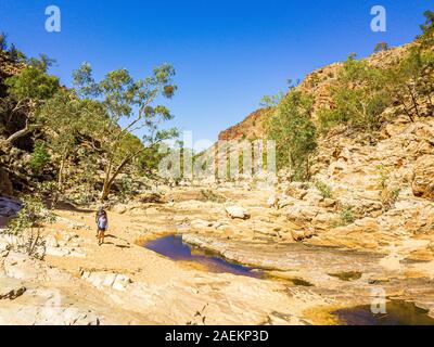 Wanderer kommen bei Redbank Gorge Wasserloch bereit für ein erfrischendes Bad im eiskalten Wasser zu schwimmen. West MacDonnell Ranges, Northern Territory, Australien Stockfoto