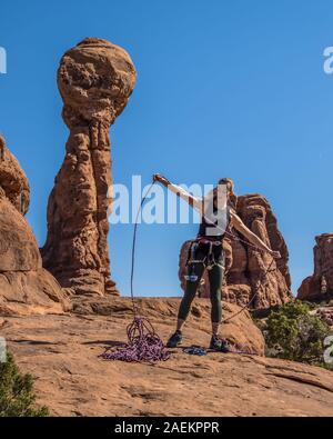 Eine attraktive junge Frau bereitet sich auf einen Felsen klettern im Garten Eden im Arches National Park in der Nähe von Moab, Utah. Stockfoto