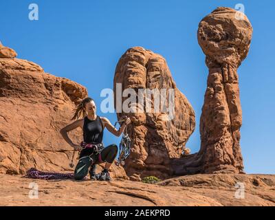 Eine attraktive junge Frau bereitet sich auf einen Felsen klettern im Garten Eden im Arches National Park in der Nähe von Moab, Utah. Stockfoto