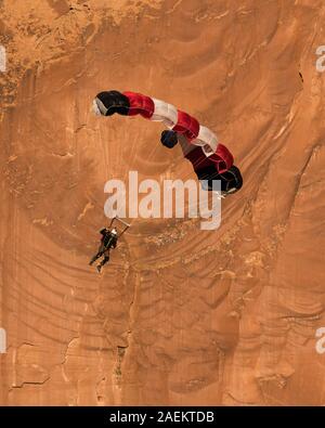 Ein Base Jumper fällt in seinem Fallschirm aus der 400-Fuß vertikale Teilfläche der Tombstone in der Kane Springs Canyon in der Nähe von Moab, Utah. Stockfoto