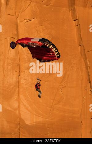 Ein Base Jumper fällt in seinem Fallschirm aus der 400-Fuß vertikale Teilfläche der Tombstone in der Kane Springs Canyon in der Nähe von Moab, Utah. Stockfoto