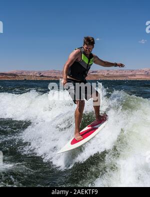 Ein wakesurfer reitet der Surf Wave mit einem Boot wake am Lake Powell, Glen Canyon National Recreation Area, Utah, USA. Stockfoto