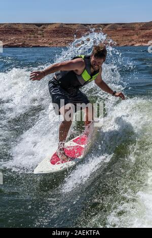 Ein wakesurfer reitet der Surf Wave mit einem Boot wake am Lake Powell, Glen Canyon National Recreation Area, Utah, USA. Stockfoto