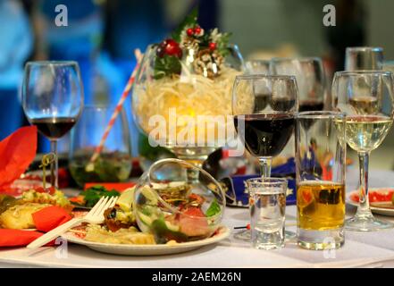 Schmutzige Teller und leeren Gläser für eine Weihnachtsfeier. Essensreste auf dem weißen Tisch. Wein, Sekt, mojito Getränke und Schlangen. Verfügbare pla Stockfoto