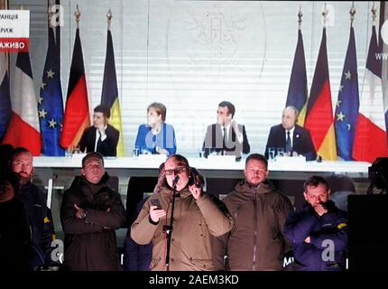 Kiew, Ukraine. 10 Dez, 2019. Die Ukrainer sehen eine gemeinsame Pressekonferenz im Anschluss an die Normandie vier Leaders Summit, Volodymyr Zelensky, Wladimir Putin, Merkel und Emmanuel Längestrich, außerhalb des Präsidialbüros in Kiew. Ein Normandie Format Gipfel mit der Teilnahme von Verantwortlichen der Ukraine, Russland, Frankreich und Deutschland hinsichtlich der Konflikte in der östlichen Ukraine wurde in Paris statt. Credit: SOPA Images Limited/Alamy leben Nachrichten Stockfoto