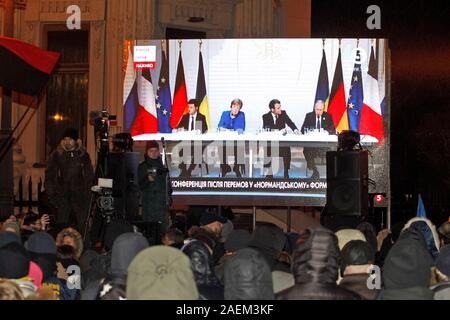 Kiew, Ukraine. 10 Dez, 2019. Die Ukrainer sehen eine gemeinsame Pressekonferenz im Anschluss an die Normandie vier Leaders Summit, Volodymyr Zelensky, Wladimir Putin, Merkel und Emmanuel Längestrich, außerhalb des Präsidialbüros in Kiew. Ein Normandie Format Gipfel mit der Teilnahme von Verantwortlichen der Ukraine, Russland, Frankreich und Deutschland hinsichtlich der Konflikte in der östlichen Ukraine wurde in Paris statt. Credit: SOPA Images Limited/Alamy leben Nachrichten Stockfoto