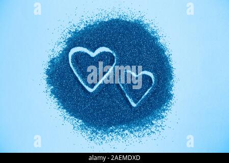 Zwei Herzen von Hand auf Blau Zucker Hintergrund dargestellt. Stockfoto