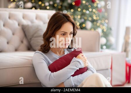 Hübsche junge Frau umarmen, Kissen und Suchen umgekippt Stockfoto